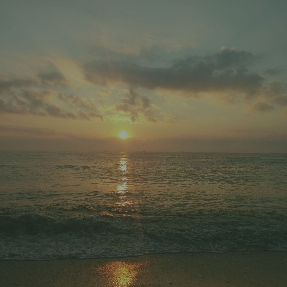 Sunset at the ocean with waves coming in and clouds